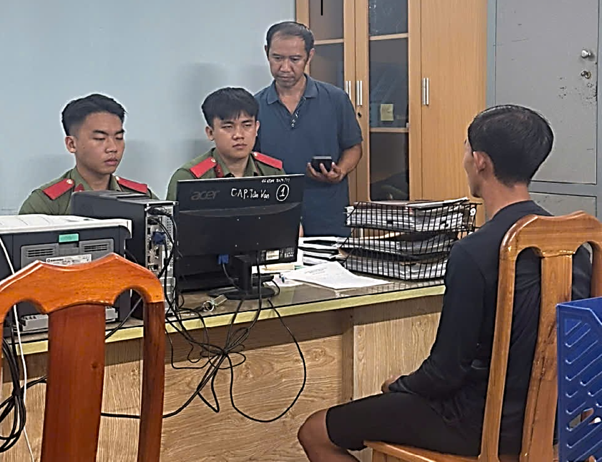 Ông Q.V.T (áo đen) tại cơ quan Công an.